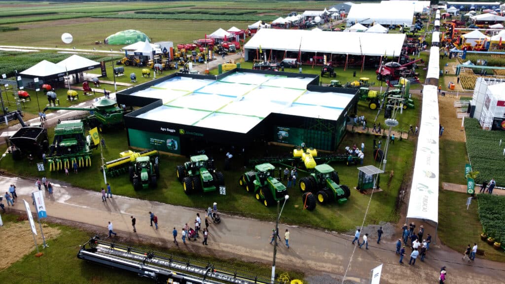 Vista aérea do estande da Agro Baggio (John Deere) montado pela LXBR no Show Safra 2025, com estrutura elevada e pátio de máquinas agrícolas.