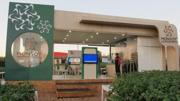 Estande externo da Monsoy montado pela LXBR, com portal verde, plataforma elevada e vitrine de cultivo de soja