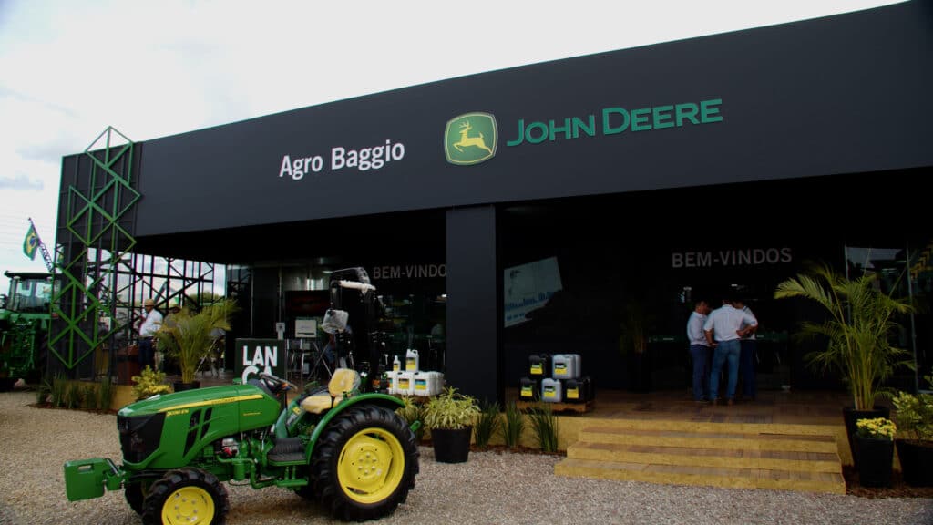 Estande da Agro Baggio, concessionária John Deere, montado pela LXBR, com fachada preta de pé-direito alto e trator em destaque