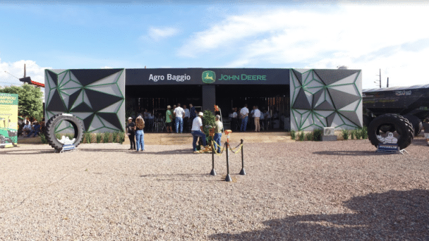 Estande da Agro Baggio (John Deere) montado pela LXBR no Norte Show, com fachada preta geométrica e pneus agrícolas na entrada.