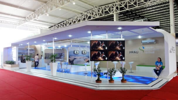 Estande em ilha da Energia Sustentável do Brasil montado pela LXBR, com cobertura suspensa branca, videowall e plataforma elevada