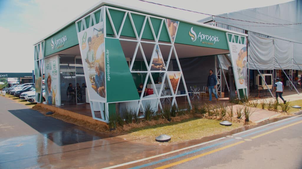 Estande da Aprosoja no Show Safra, com estrutura treliçada branca e segundo pavimento em painéis gráficos, montado pela LXBR